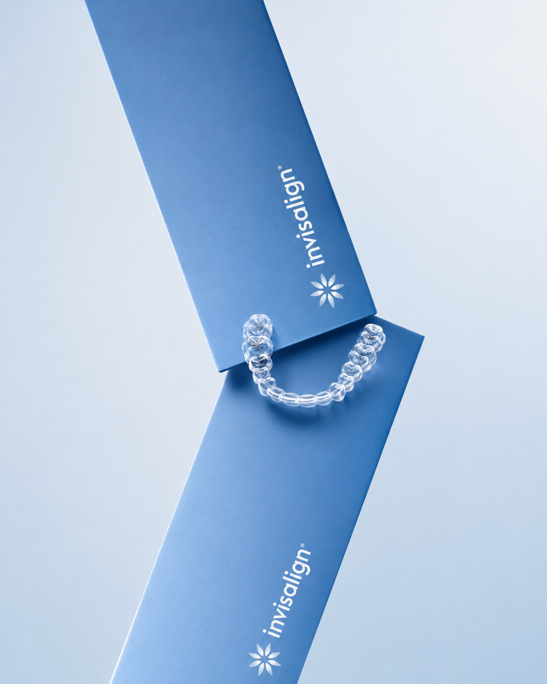 Clear Invisalign aligner displayed between two blue Invisalign presentation boxes at Cadbury Dental, Birmingham